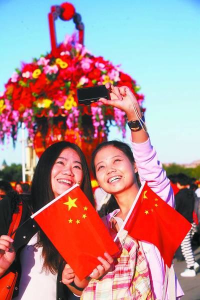 9月30日,两名女孩手拿国旗在北京天安门广场拍照留念.